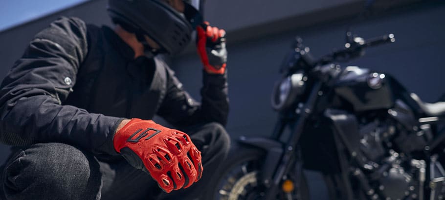 Motard équipé d'un blouson moto textile à côté de son roadster